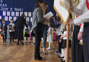 Nauczycielka wręcza uczniom dyplomy.