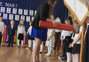 Pani Dyrektor pasuje wielkim ołówkiem uczniów klas pierwszych.