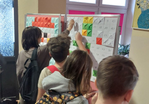 Uczniowie przyklejający poszczególne elementy na planszy, z których powstanie obraz.