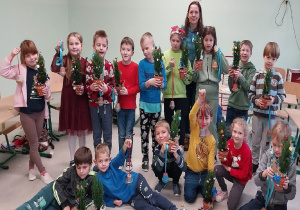 Zdjęcie klasy 1b ze świątecznymi drzewkami i karmnikami dla ptaków.