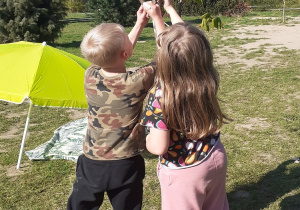Dzieci ze świetlicy ozdabiają kropkami drzewo na placu zabaw.