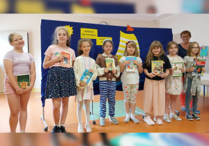 Dziewięcioro dzieci pokazuje dyplomy otrzymane za udział w konkursie.