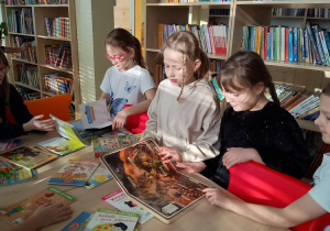 Uczniowie klasy 1b oglądają książki w bibliotece szkolnej.
