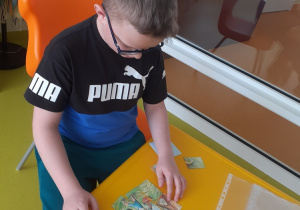 Uczeń układa puzzle w bibliotece.