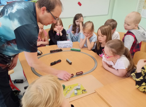 Rodzic demonstruje uczniom modele kolejowe.