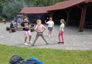 Uczniowie bawią się przy wiacie leśnej.