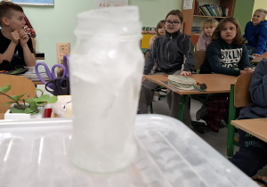 Zamarznięta woda wystająca ponad brzeg słoika.