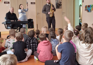 Muzyk prezentuje grę na saksofonie.