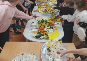 Uczniowie wyciągają rączki po zdrowe przekąski.