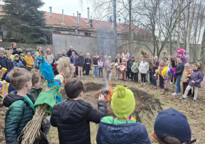 Uczniowie z marzannami przy ognisku.