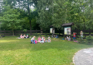 Uczniowie odpoczywają na leśnej polanie.