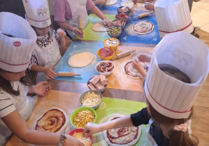 Uczniowie w pizzerii podczas robienia pizzy.
