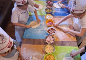 Uczniowie w pizzerii podczas robienia pizzy.