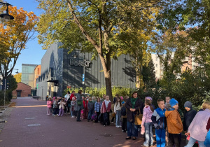 Uczniowie i nauczyciele stoją przed budynkiem teatru.